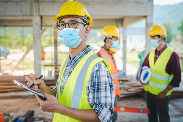 man on construction site wearing hard helmet and face mask